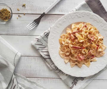 Farfalle con crema de parmesano, speck y pistachos