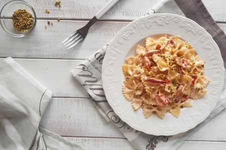 Farfalle con crema de parmesano, speck y pistachos