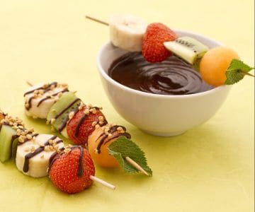 Brochetas de fruta con salsa de chocolate y granillo de avellanas