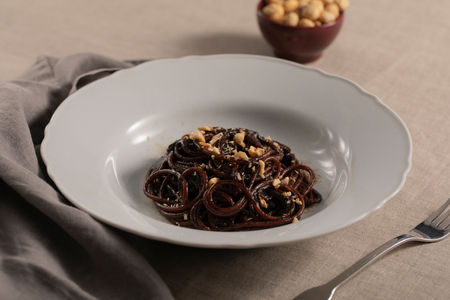 Espaguetis con crema de ajo negro, regaliz y avellanas
