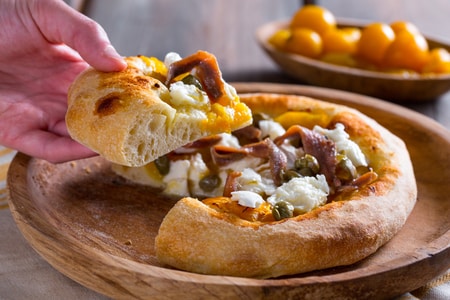 Pizza con tomatitos amarillos, anchoas y alcaparras