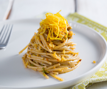 Spaghettoni con colatura de anchoas, pistachos y limón confitado