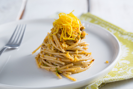 Spaghettoni con colatura de anchoas, pistachos y limón confitado
