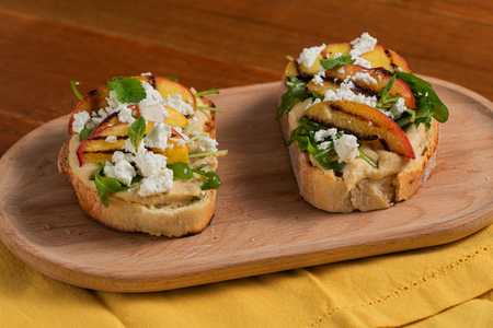 Tostada con hummus, melocotones a la parrilla, feta y rúcula