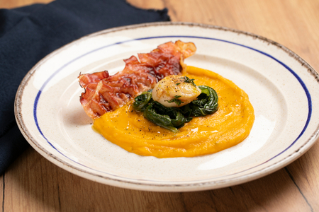 Vieiras sobre crema de calabaza con hierbas y speck