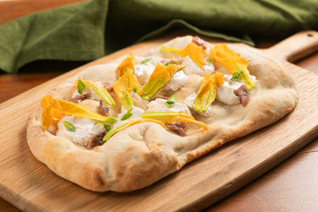 Pinsa con flores de calabacín, anchoas y crema de queso