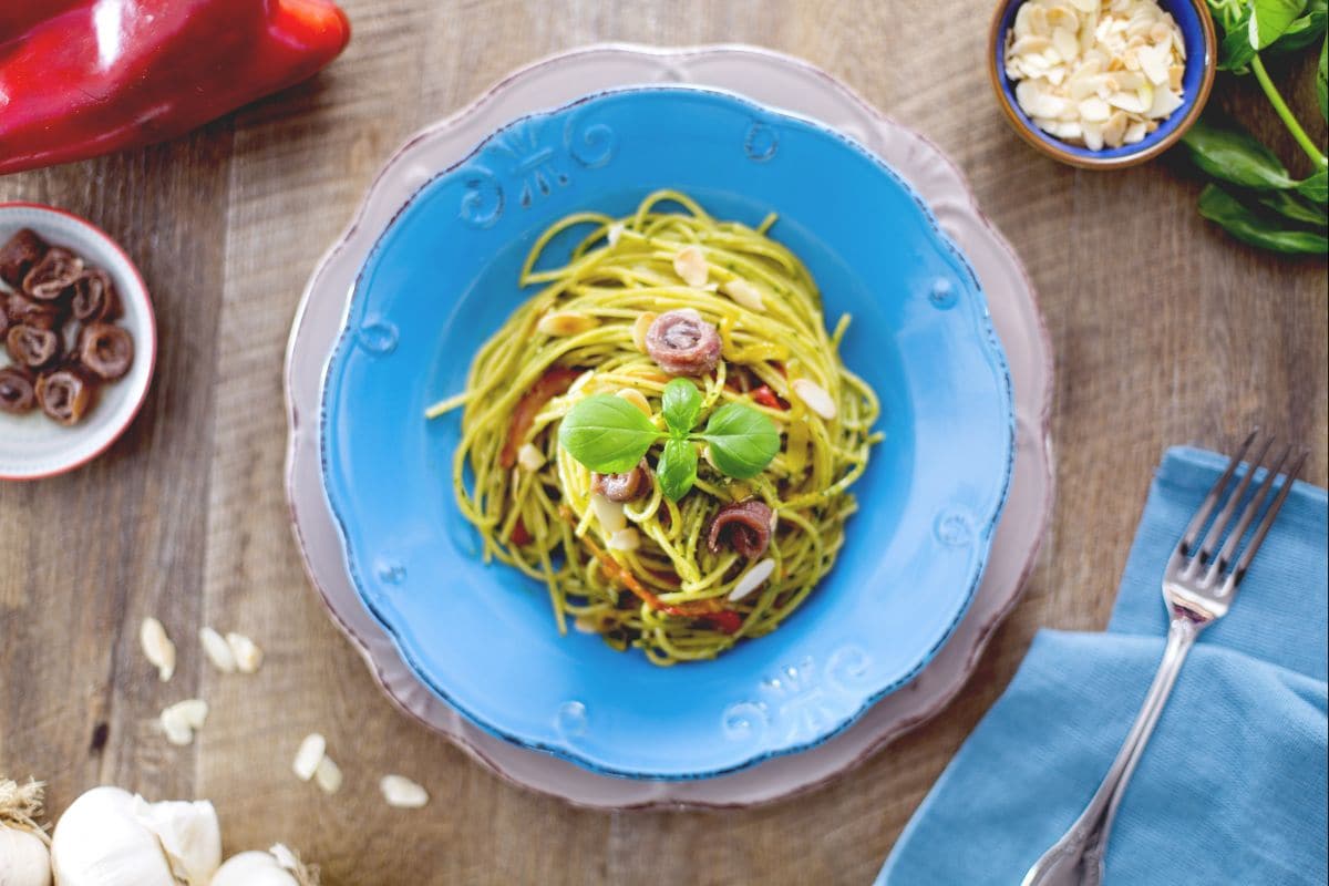 Espaguetis al pesto con anchoas y pimientos