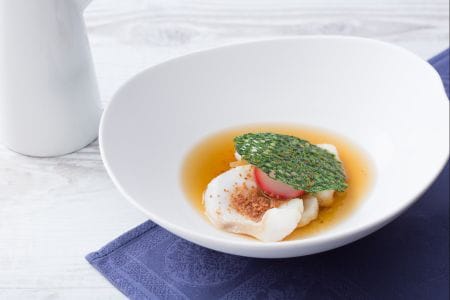 Caldo de jamón, bacalao desmigado con pan crujiente y rabanitos